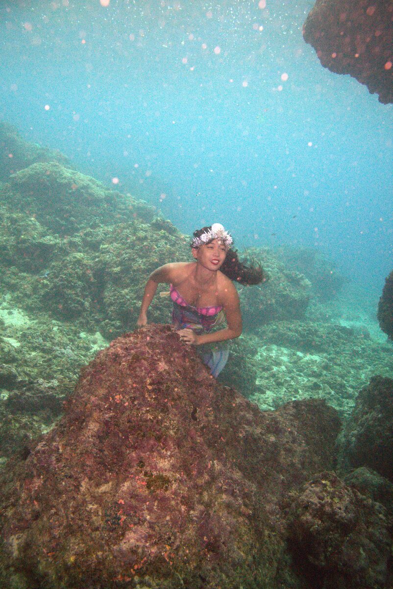 Mermaid Giona resting on a coral outcrop