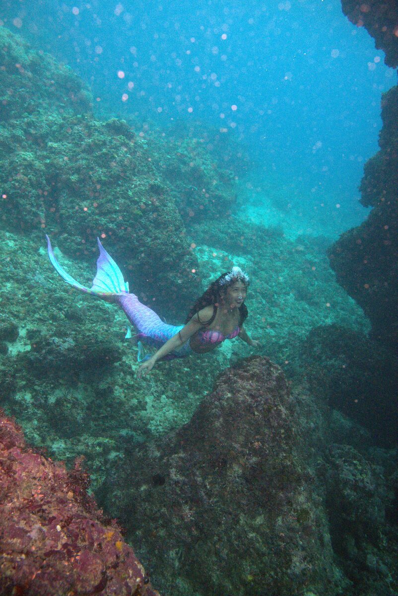 Mermaid Giona swimming past a coral reef